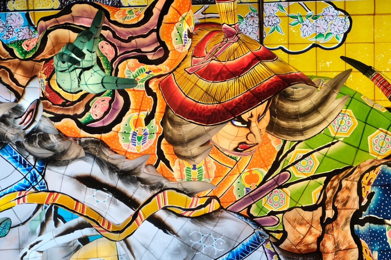 Il dettaglio dipinto di un carro Nebuta: il volto di un guerriero dai colori vivaci sulla carta illuminata