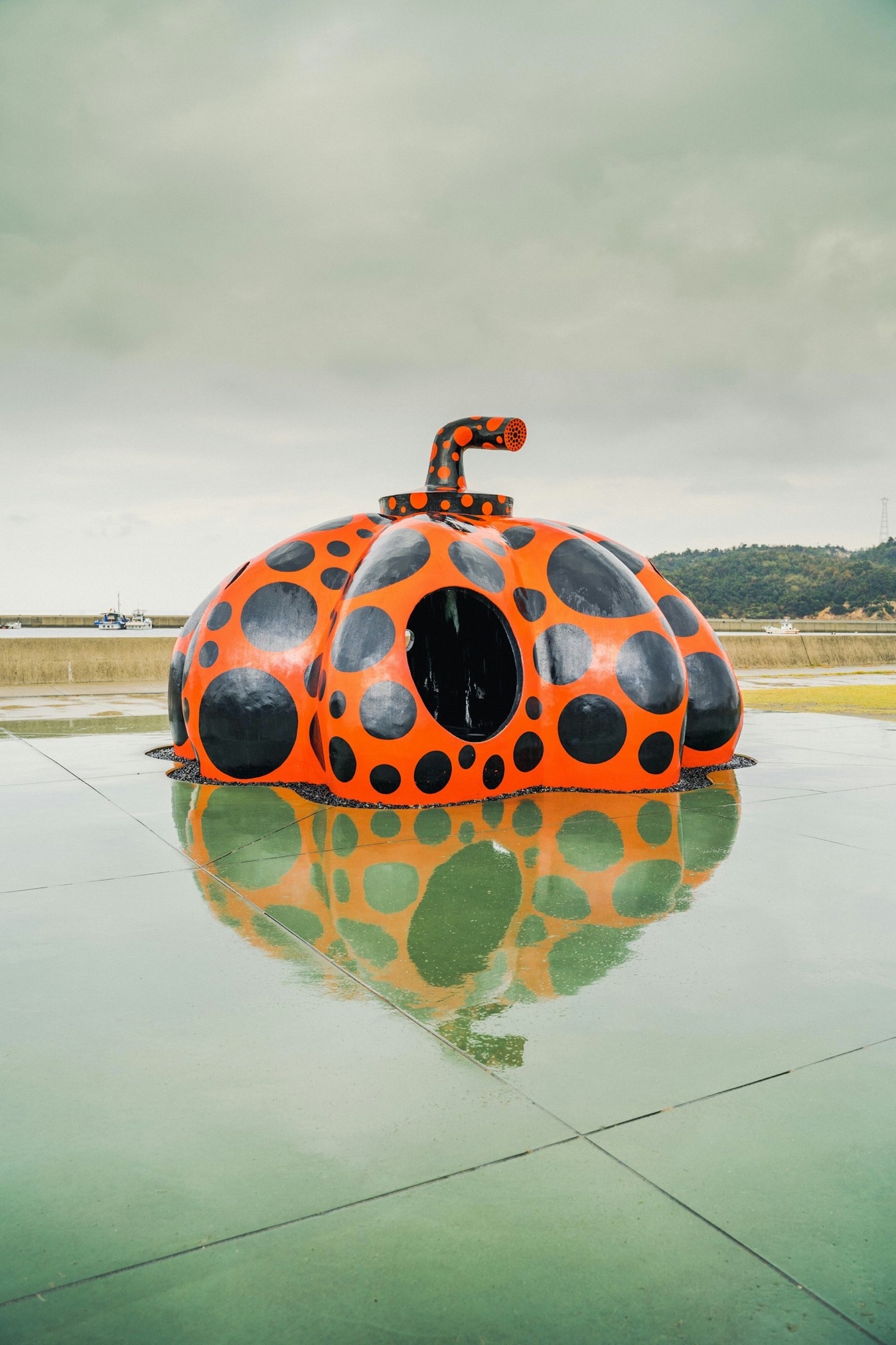 La zucca rossa a pois di Yayoi Kusama a Naoshima, con il riflesso sull'acqua