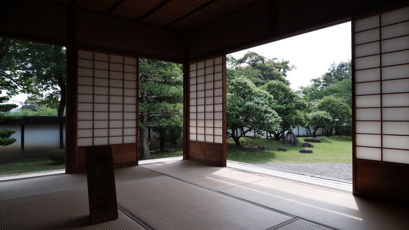 Una stanza in tatami con le porte scorrevoli di carta aperte su un giardino giapponese curato