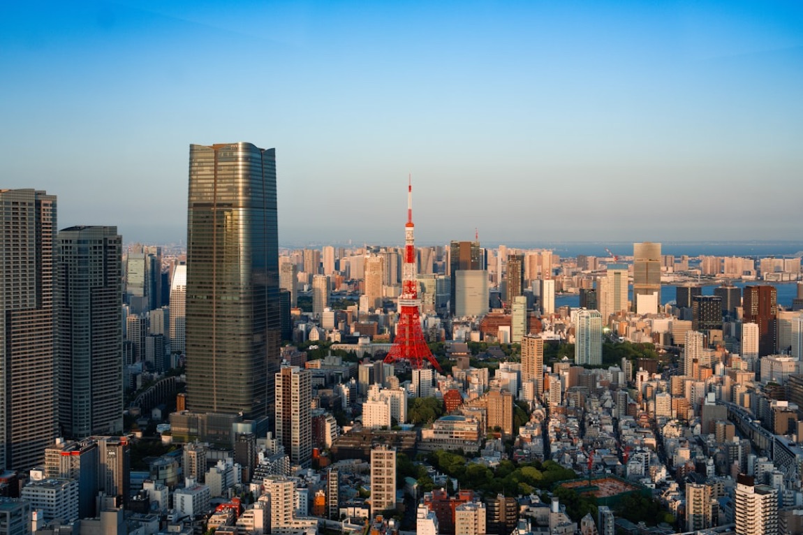 Il panorama di Tokyo dall'alto al tramonto, con la Tokyo Tower rossa che spicca tra i grattacieli fino alla baia