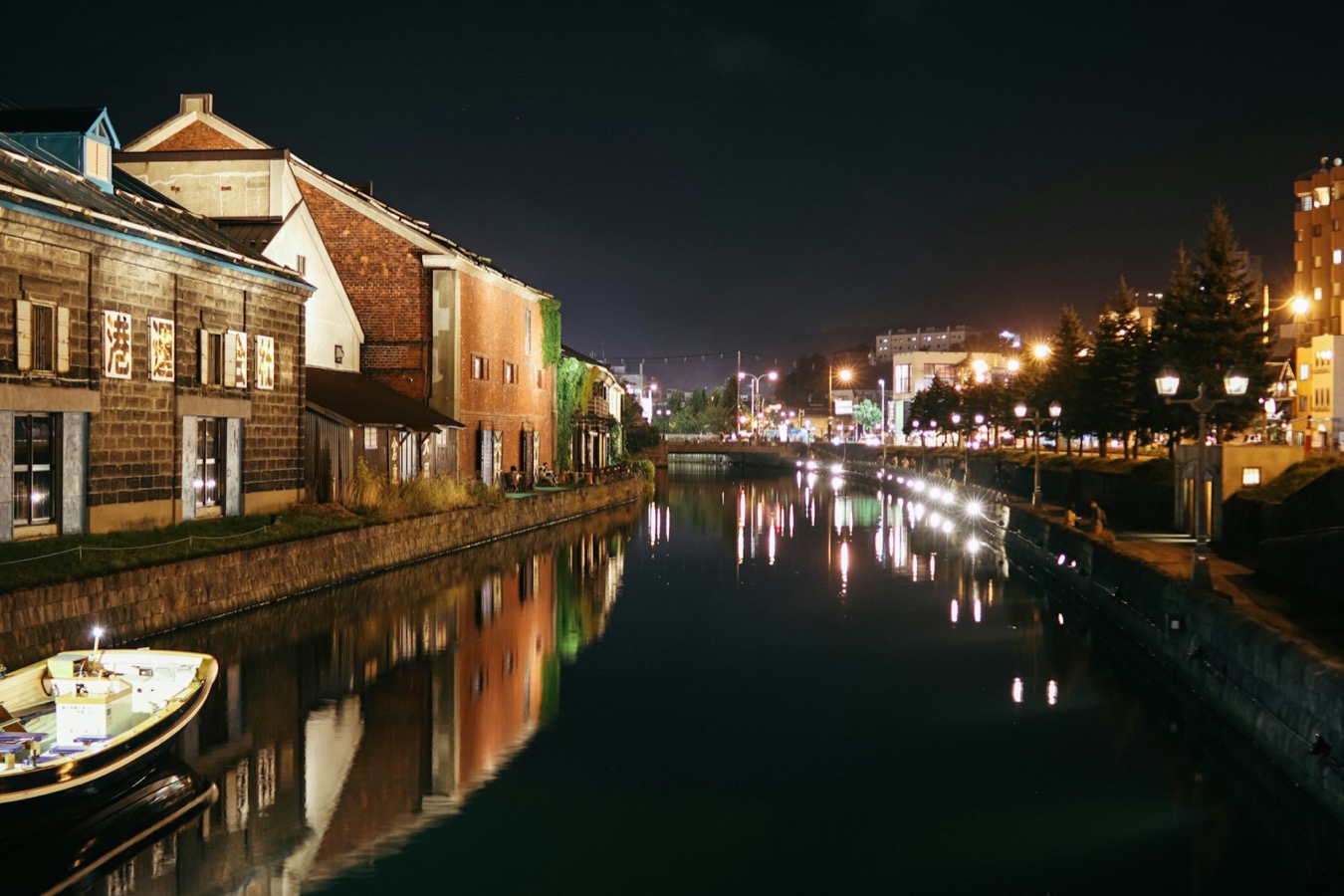 Il canale di Otaru di sera, con i magazzini illuminati e i riflessi caldi sull'acqua
