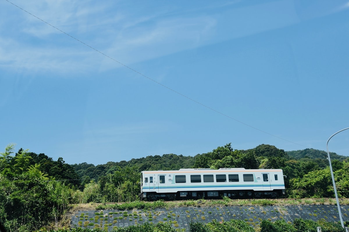 Un treno locale giapponese attraversa la campagna sotto un cielo azzurro