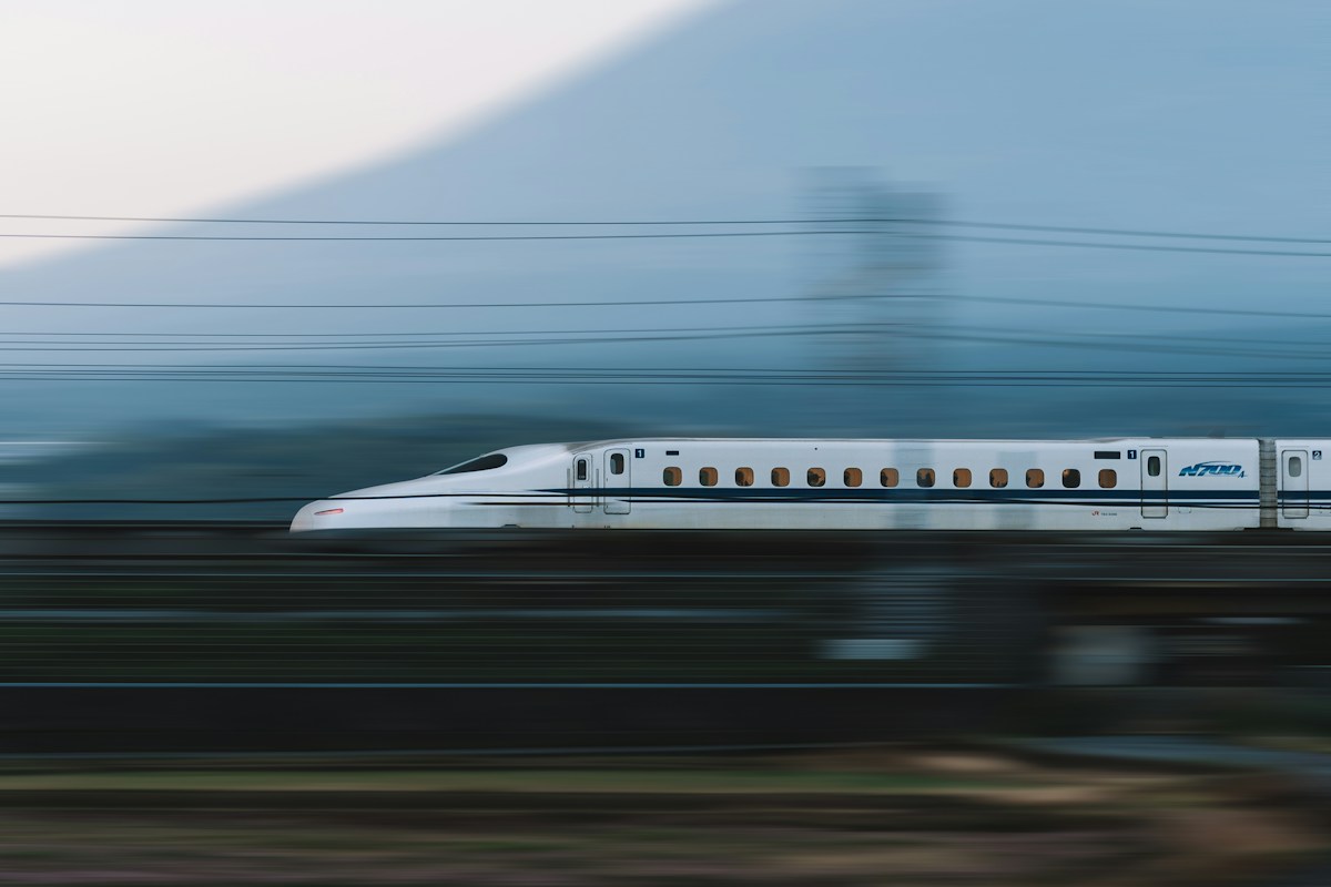 Lo Shinkansen N700 sfreccia ad alta velocità lungo i binari con il profilo del Monte Fuji sullo sfondo