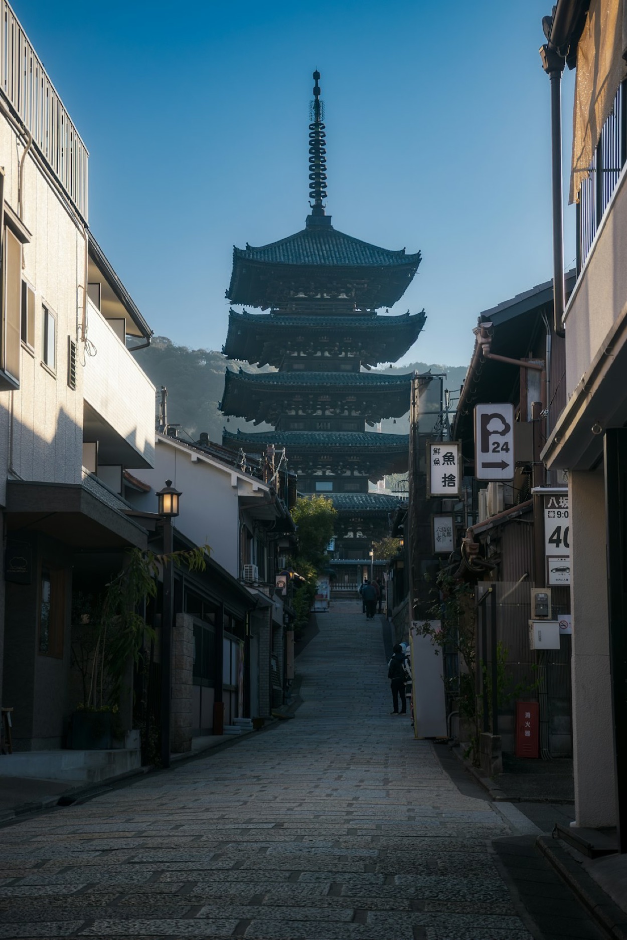 La pagoda di Yasaka che si staglia in fondo a una stradina tradizionale di Kyoto, sotto un cielo azzurro