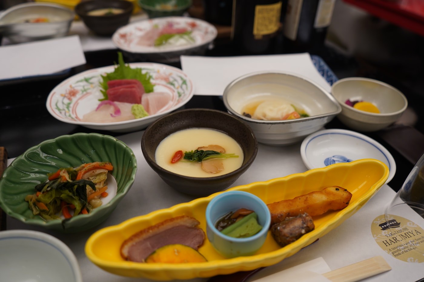 Un pasto giapponese con molti piccoli piatti: sashimi, chawanmushi e contorni in ciotole di ceramica