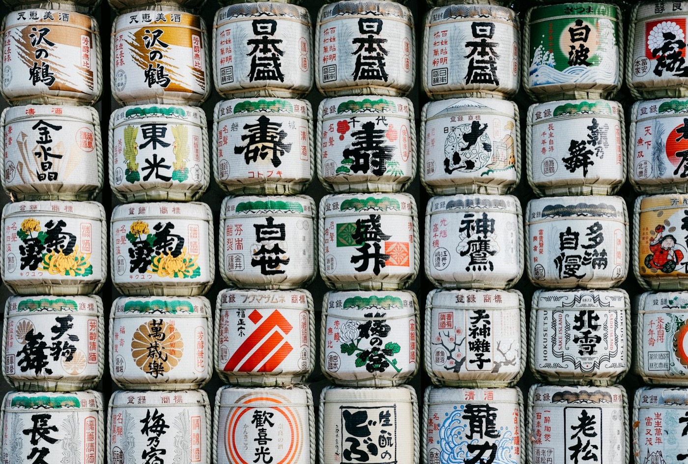 Una parete di botti di sake decorate con etichette in kanji, offerte tradizionali giapponesi