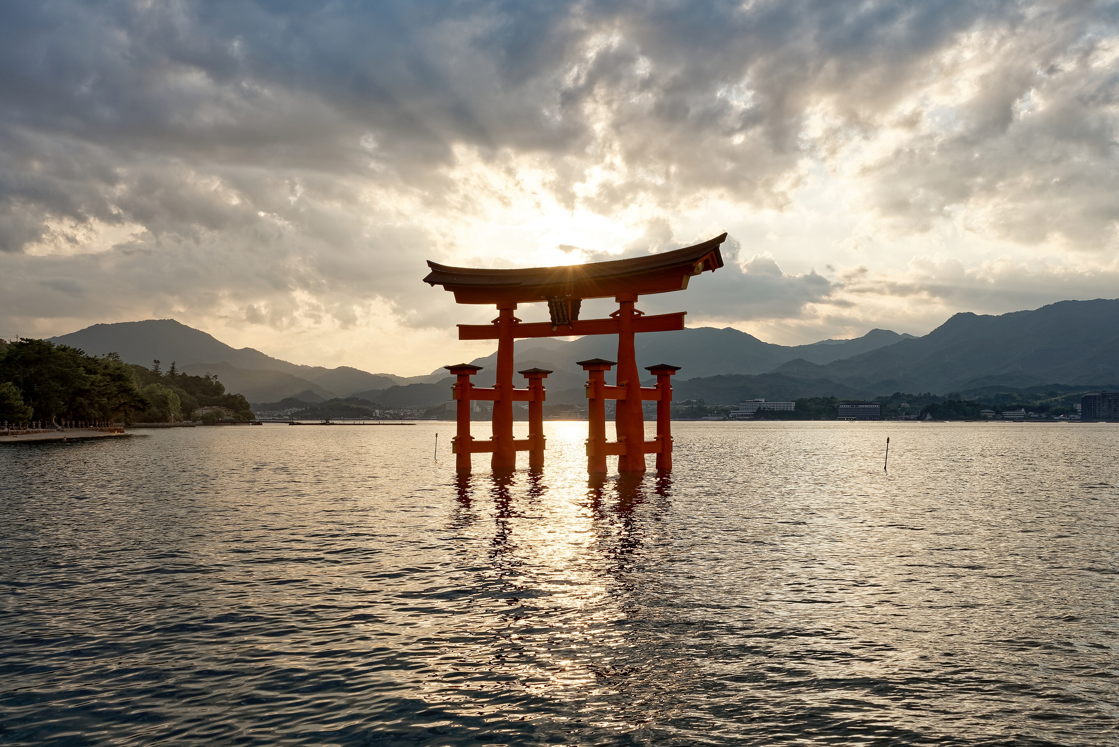 Il santuario di Itsukushima illuminato al tramonto con il riflesso nell'acqua
