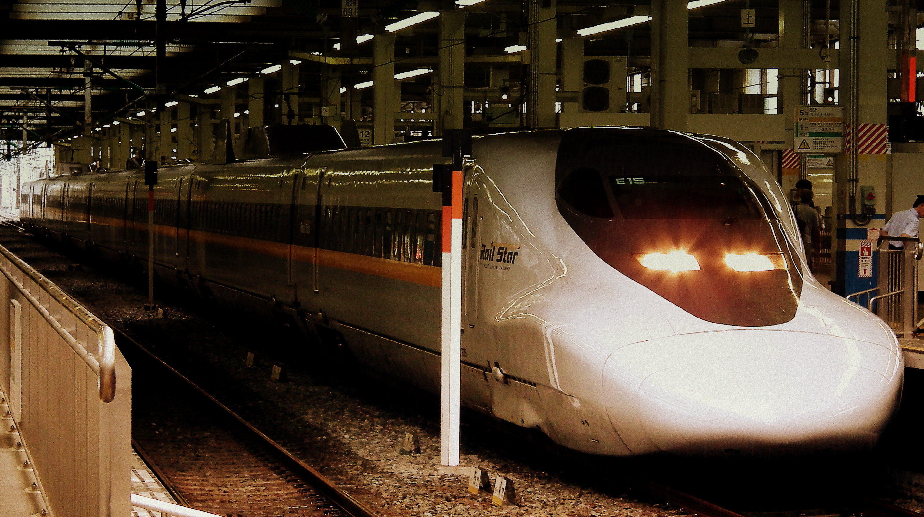 Il treno Shinkansen in stazione con la livrea bianca e il muso aerodinamico