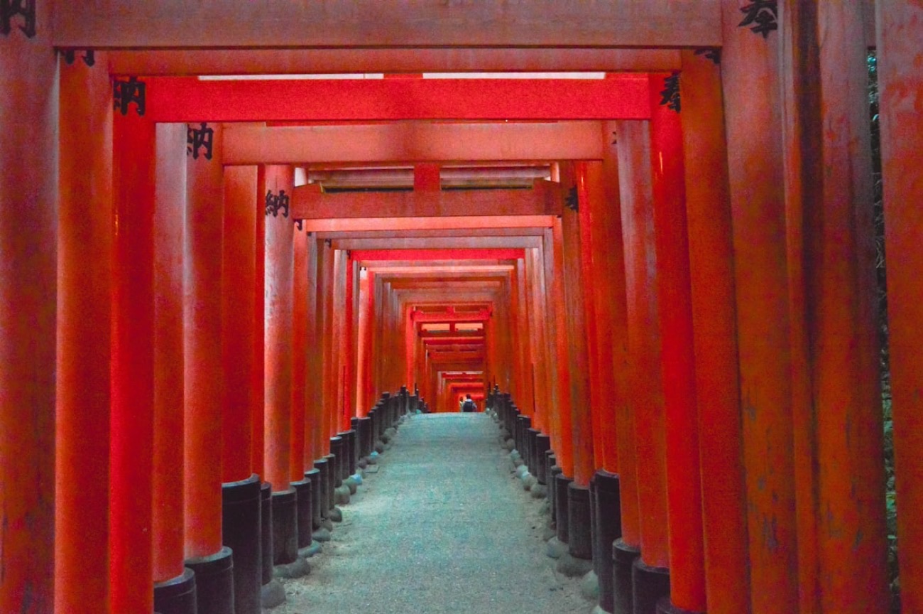 Il celebre tunnel di mille torii rossi di Fushimi Inari, a Kyoto, con le iscrizioni nere dei donatori sui pilastri