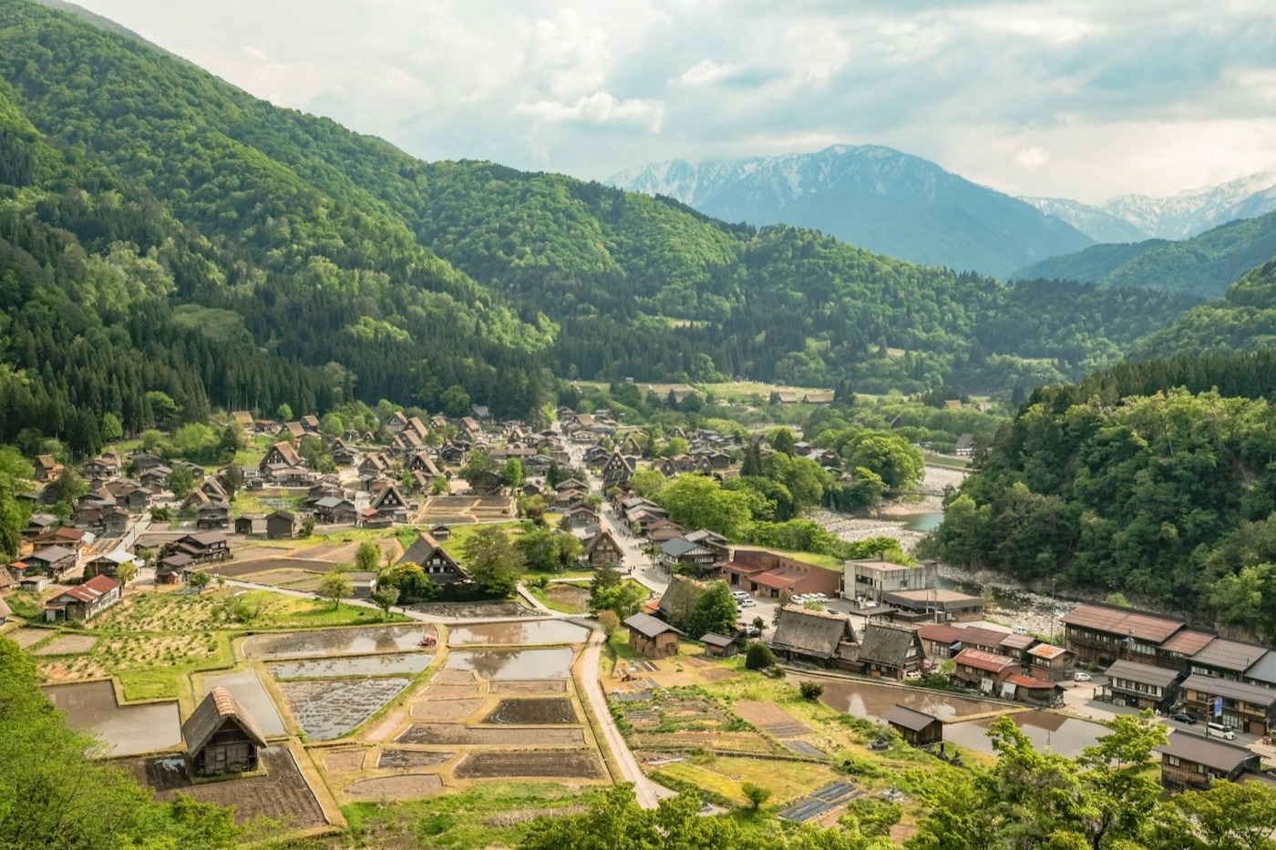 Vista panoramica di Shirakawa-go dall'alto, con le case dai tetti di paglia tra i campi verdi e le montagne