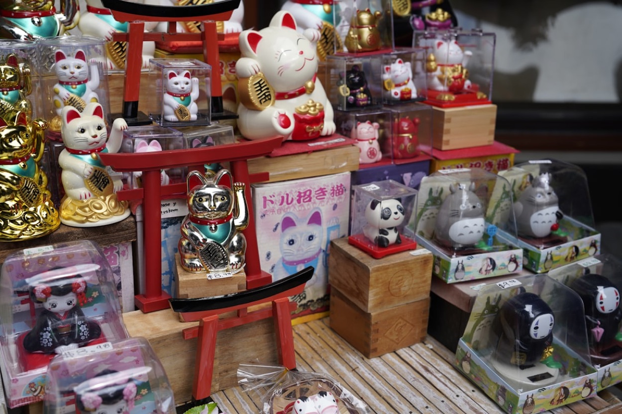 Un negozio di souvenir giapponese pieno di gatti portafortuna maneki-neko e personaggi, colorato e allegro