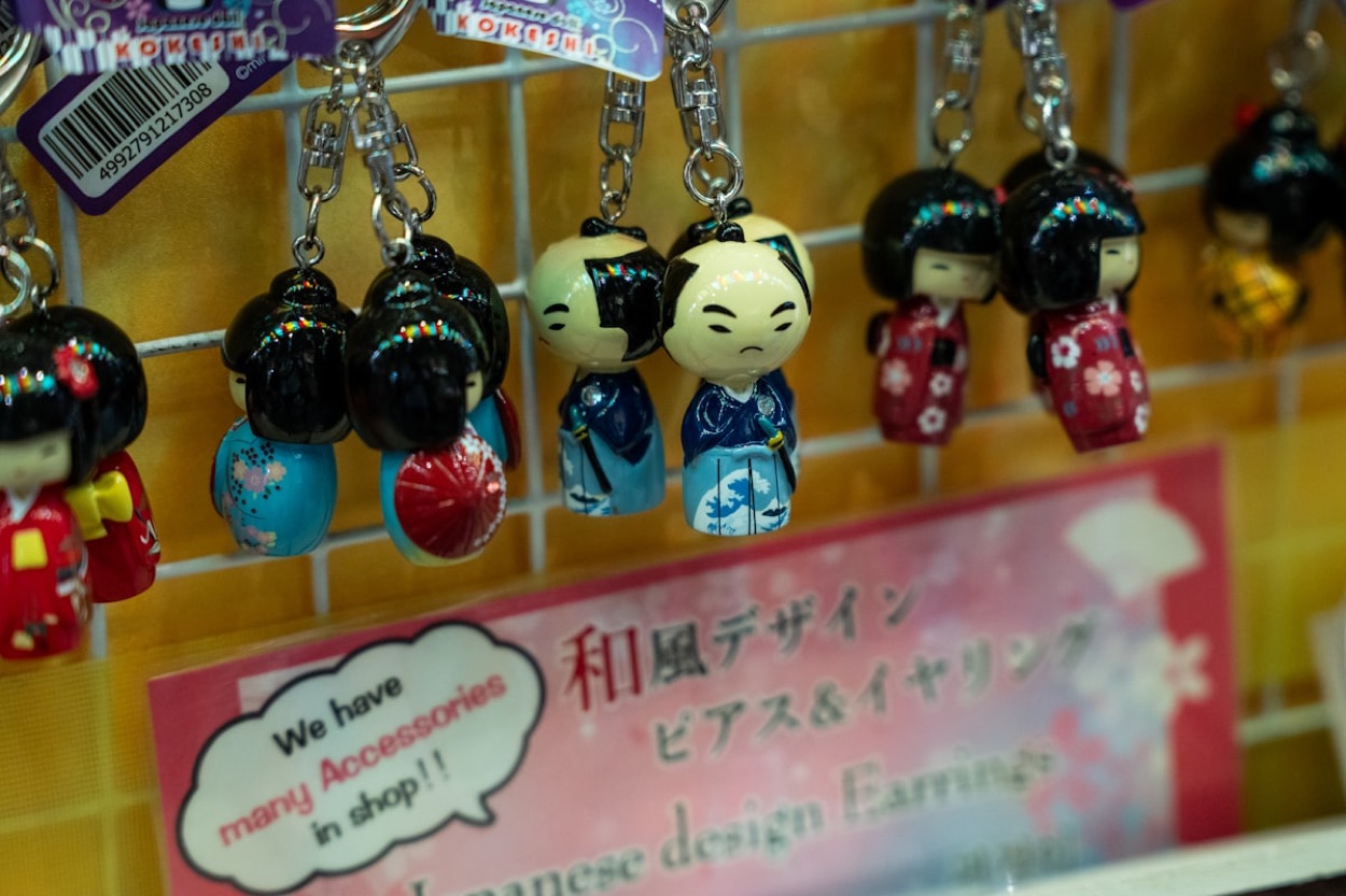 Portachiavi giapponesi a forma di bamboline kokeshi in kimono, colorati, appesi in un negozio di souvenir