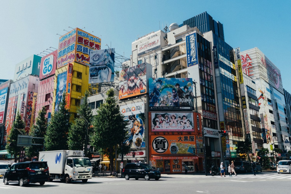 Le insegne luminose al neon di Akihabara di notte, con riflessi sull'asfalto bagnato
