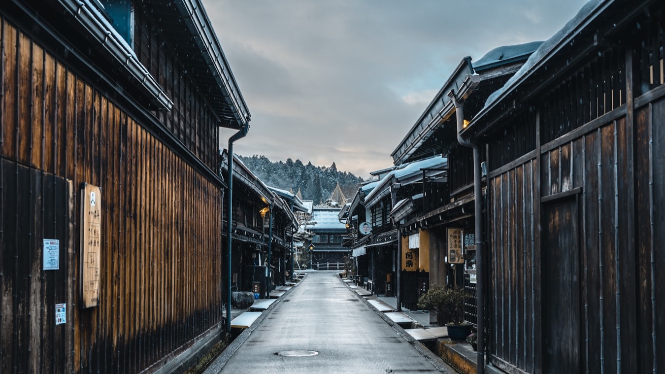Un vicolo della città vecchia di Takayama, con le facciate di legno e le montagne innevate in fondo