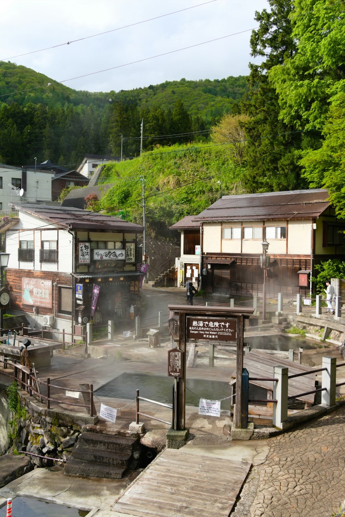 Il paese termale di Nozawa Onsen, con un bagno pubblico, vapore che sale dall'acqua calda e insegne in giapponese