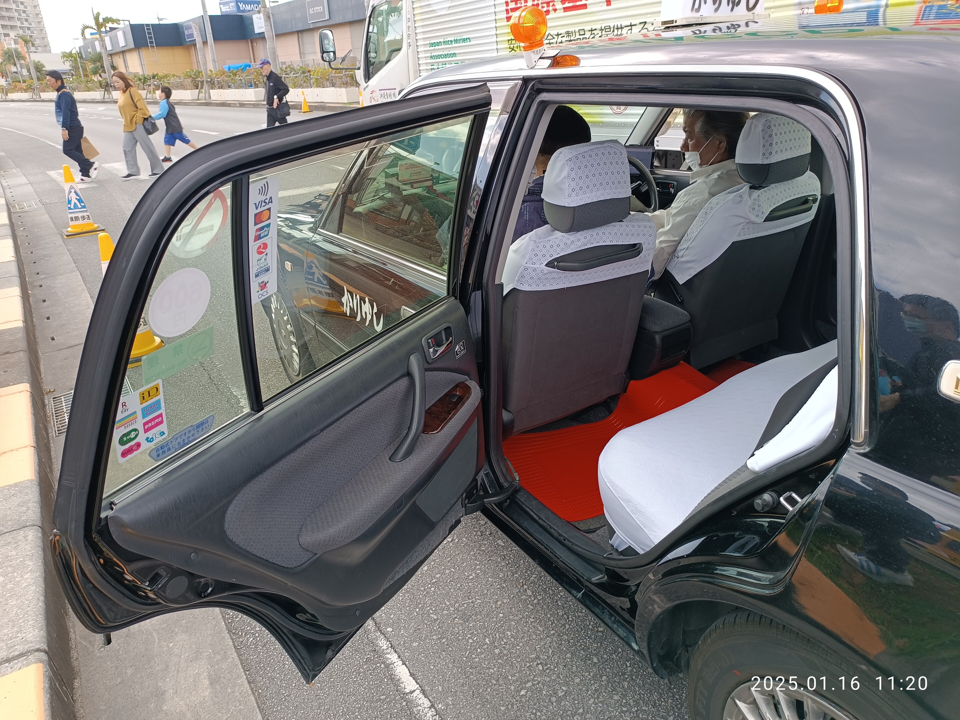 La portiera automatica di un taxi giapponese aperta, con l'autista in guanti bianchi al volante