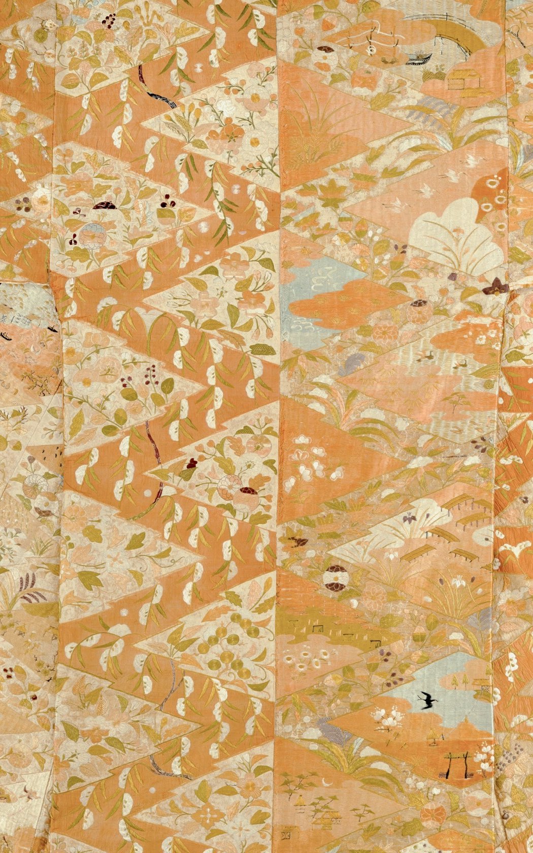 Un antico tessuto di seta giapponese, ricamato a mano con fiori, gru e piccoli paesaggi su fondo color albicocca