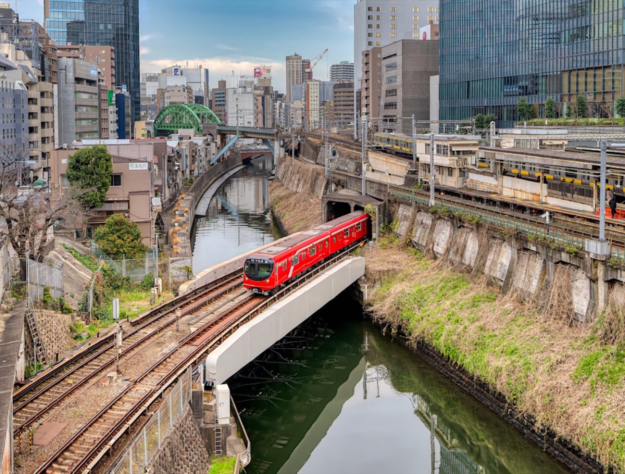 Un treno rosso della metropolitana di Tokyo attraversa un ponte sul fiume a Ochanomizu, tra i grattacieli