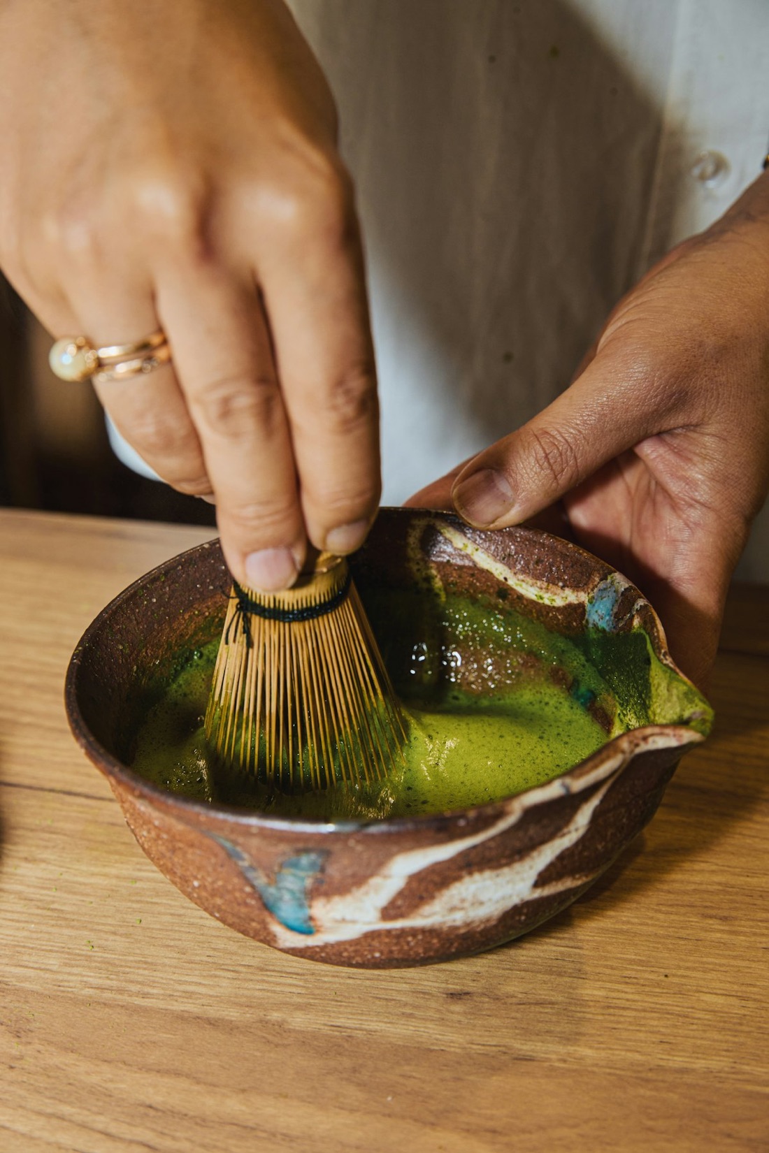 Il matcha in polvere di Uji, verde brillante, servito in una tazza di ceramica artigianale con la schiuma sul dessus