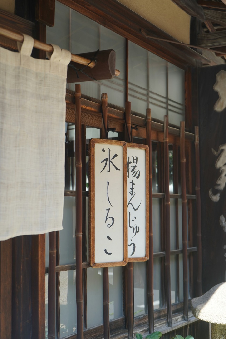 L'insegna di un negozio tradizionale giapponese di dolci, con scritte in calligrafia (age-manju e kōri-shiruko) e un noren di stoffa