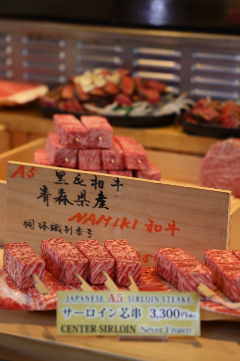Cubi di wagyu A5 dalla marezzatura intensa, esposti su un banco con un cartello giapponese "A5 黒毛和牛"