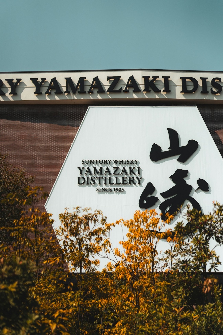 L'insegna della distilleria Yamazaki di Suntory, "Yamazaki Distillery since 1923", con i caratteri 山崎 e gli alberi d'autunno