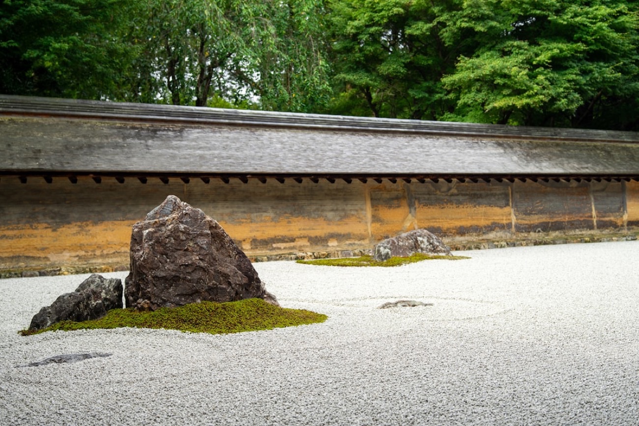 Il giardino di pietre del tempio Ryoan-ji a Kyoto: ghiaia bianca rastrellata, rocce con il muschio e l'antico muro di terra sullo sfondo